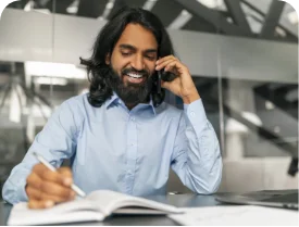 Man talking on the phone while writing in a notebook