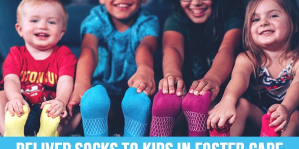 four kids wearing socks from the socktober initiative at foster love