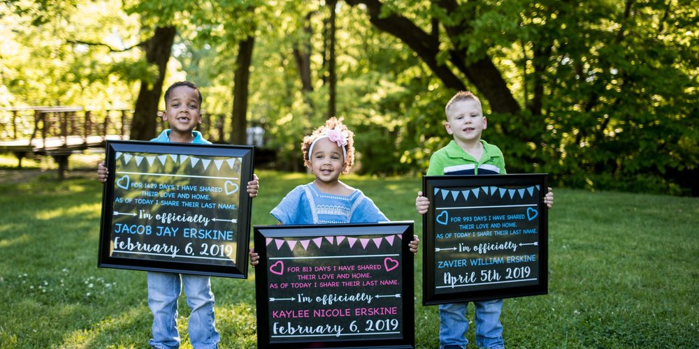 three little kids holding framed message apart of their adoption story