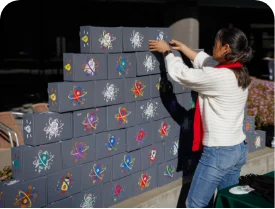Volunteer adding their STEM box to the top of a pyramid of STEM boxes