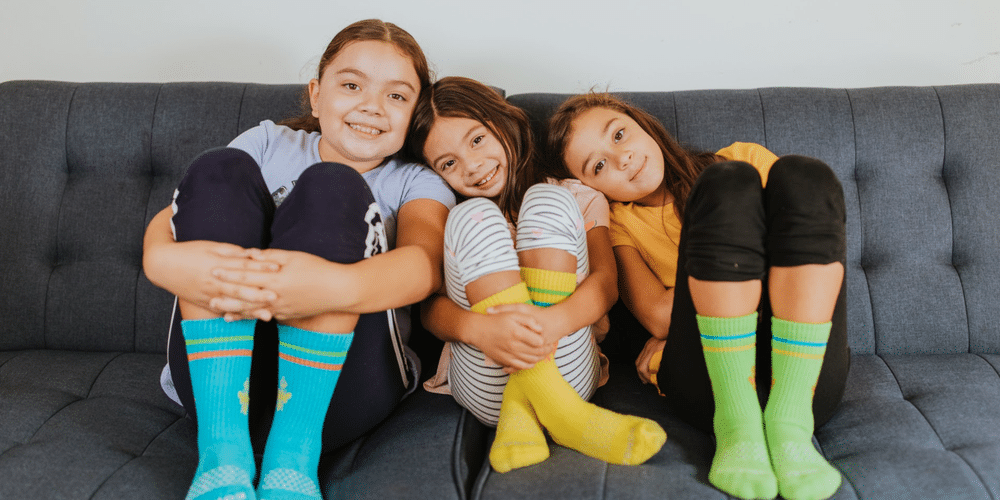 three young girls sitting on the couch celebrating socktober