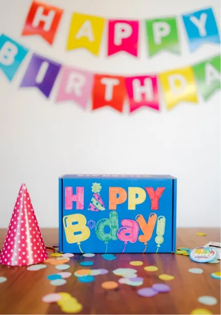 decorated birthday box, confetti on table, birthday banner, and hat