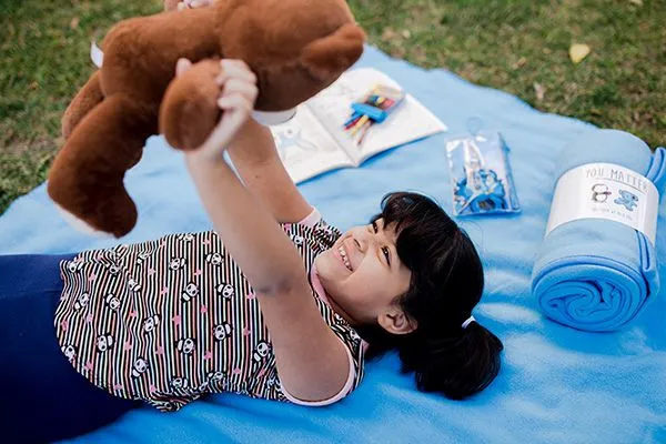 child holding up snuggle kit bear