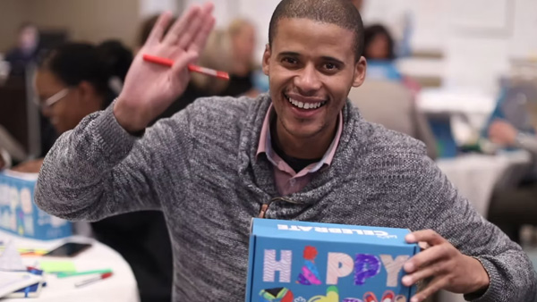 Man waving while holding his decorated Birthday Box service project