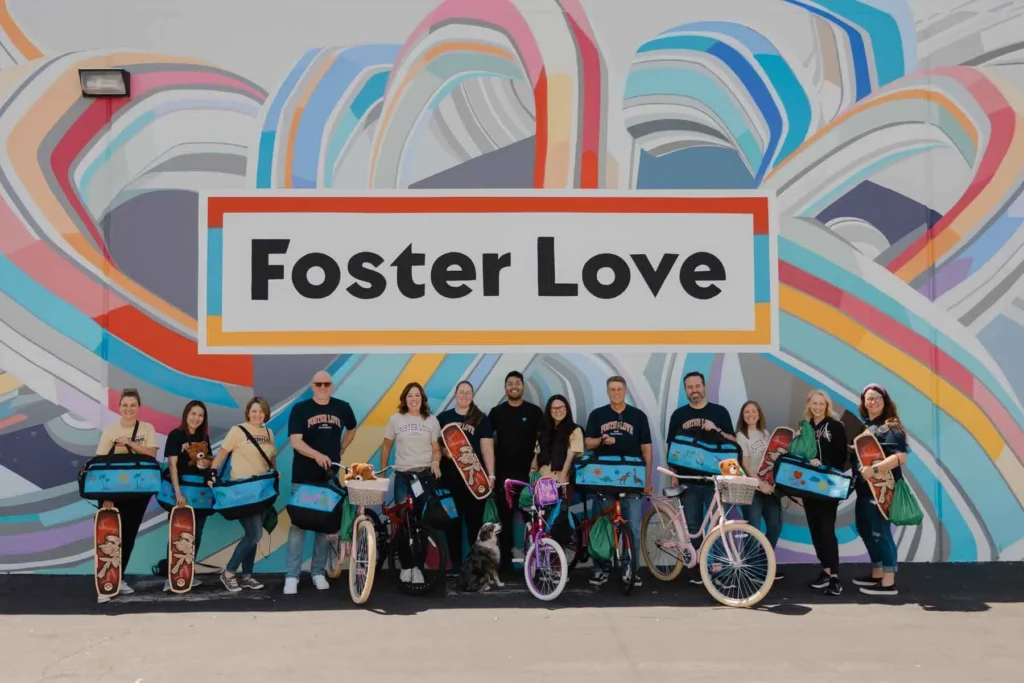 Volunteers with their bikes and sweet case panels in front of foster love mural