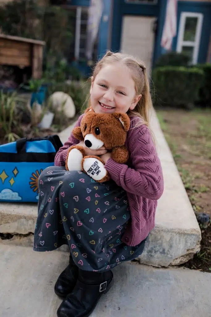 girl hugging bear from sweet case sitting on steps