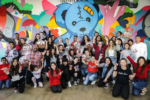 Volunteers posing in front of a Foster Love mural