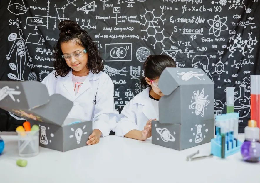 Two girl smiling as they open their STEM boxes