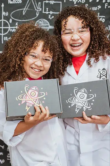 Two girls wearing lab coats posing with their STEM Boxes