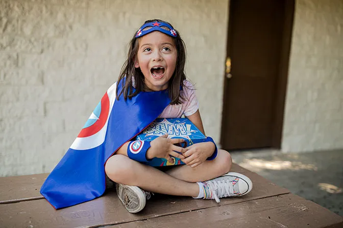 Girl wearing her superhero mask and cape