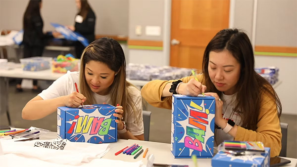 Two women sitting at a table decorating their Superhero Boxes