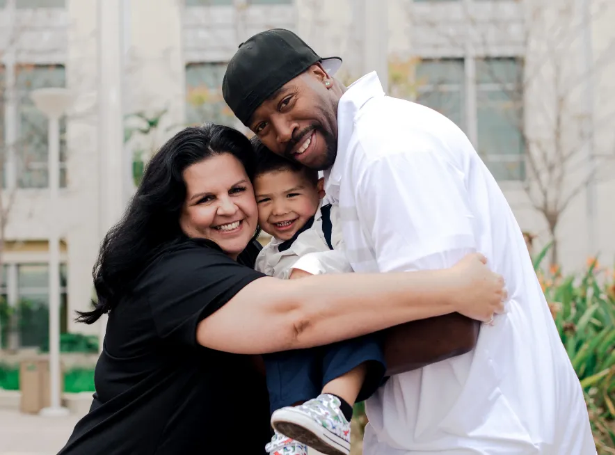 Parents hugging their adoptive son outside the courthouse