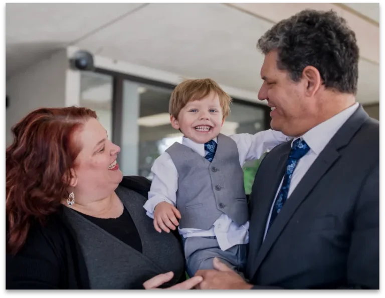 Parents smiling at their son as they hold him outside the courthouse