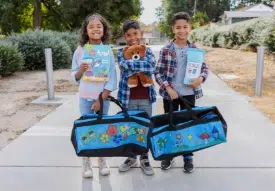 Three kids holding their decorated Sweet Case duffles