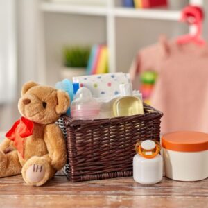 A basket of baby supplies and a teddy bear on a table