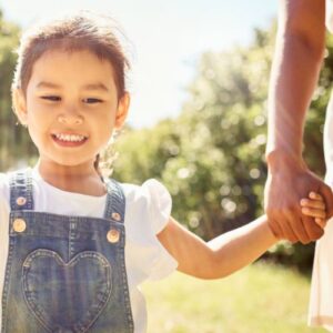 girl holding hands with mom outdoors