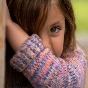 Girl looking at camera hiding behind a wall