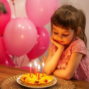 little girl smiling down at her birthday cake