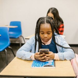 girl on phone at desk in school