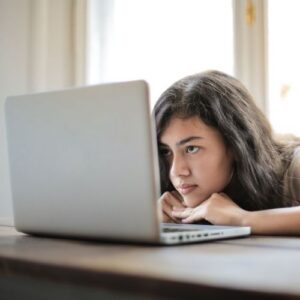 girl looking at laptop, chin on desk